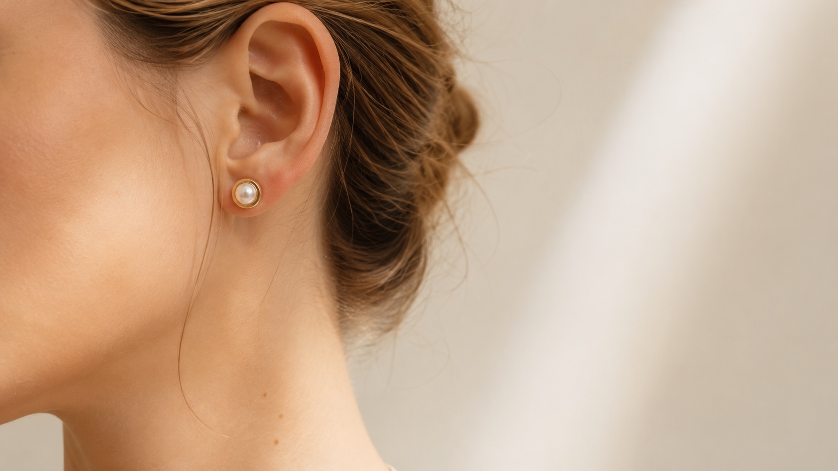 The Half Pearl stud worn close to the ear in soft window light.